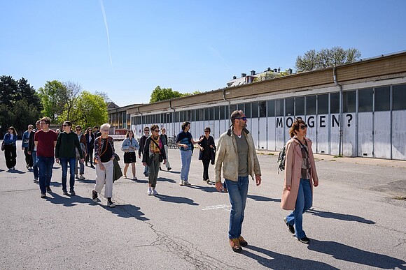 Tour: Biofabrique Vienna am Nordwestbahnhof 2 Mehrere Personen nehmen an Tour am Nordwestbahnhof Areal teil; gehen gemeinsam den Weg entlang