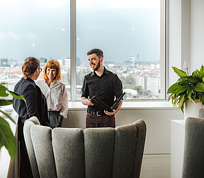 Drei Personen unterhalten sich im Stehen_Querformat