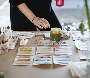 Person experimentiert auf Papier mit "Wiener Farben"