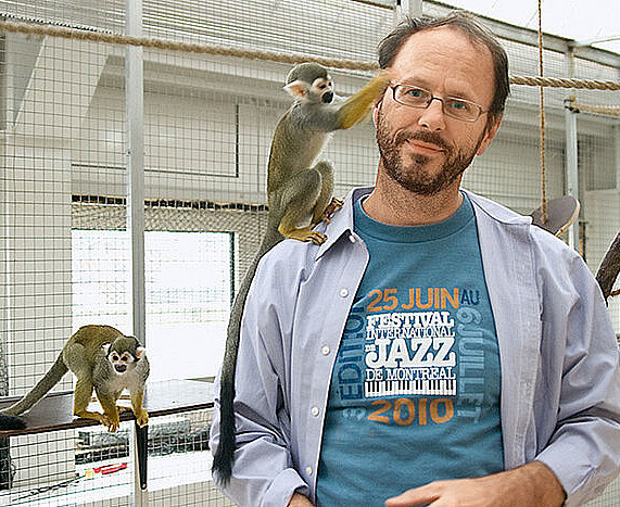 EIn Mann im weißen Kittel kümmert sich liebevoll um zwei Äffchen