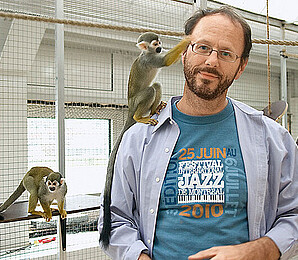 EIn Mann im weißen Kittel kümmert sich liebevoll um zwei Äffchen