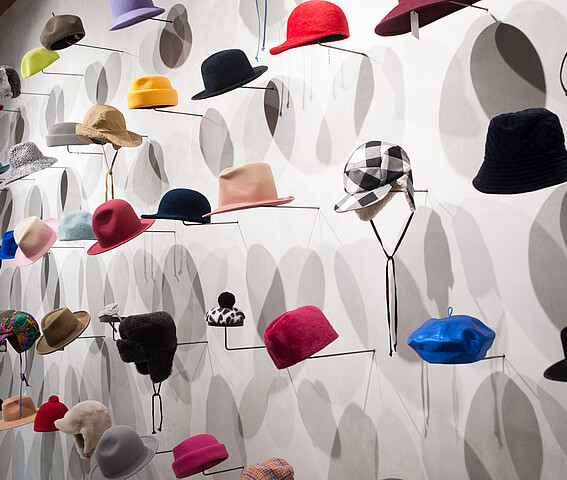 Hutmode Biester: Viele unterschiedliche Hüte sind an einer Wand ausgestellt