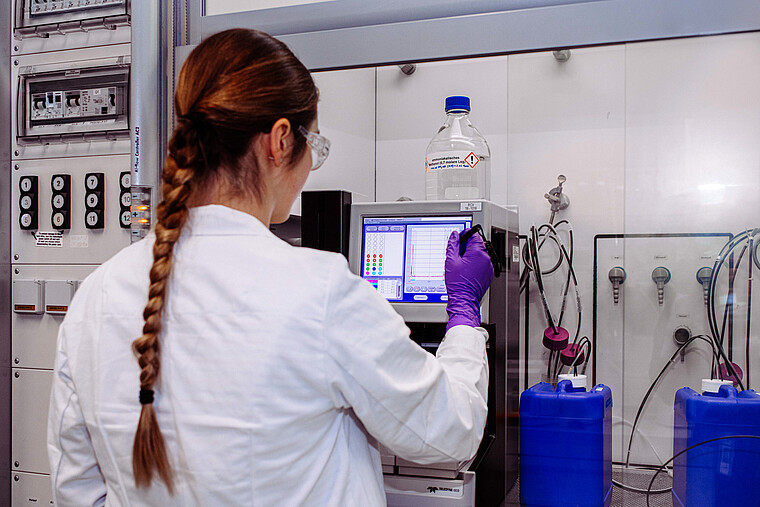 Eine Forscherin arbeitet in einem Labor und füllt Flüssigkeit um.