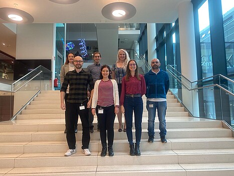 A team of scientists standing on steps inside an office