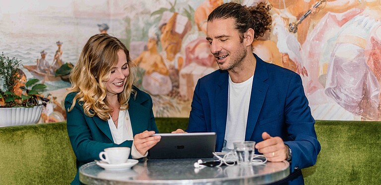 Eine Frau und ein Mann sitzen gemeinsam an einem Tisch und arbeiten an einem Computer