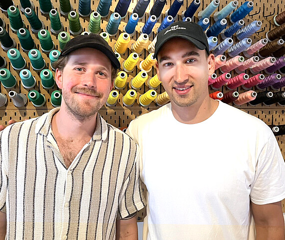 Junge Männer vor Wand mit buntem Garn