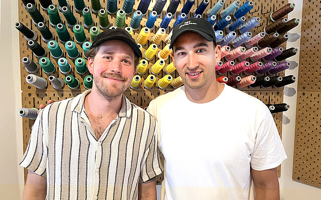 Junge Männer vor Wand mit buntem Garn