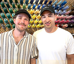 Junge Männer vor Wand mit buntem Garn