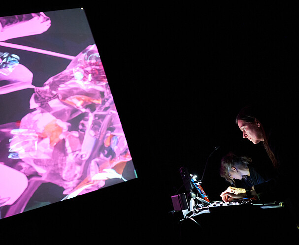 Frau bedient Mischpult vor Leinwand mit Projektion