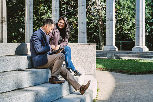 Eine Frau und ein Mann im Gespräch sitzen in einem Park auf Stufe.