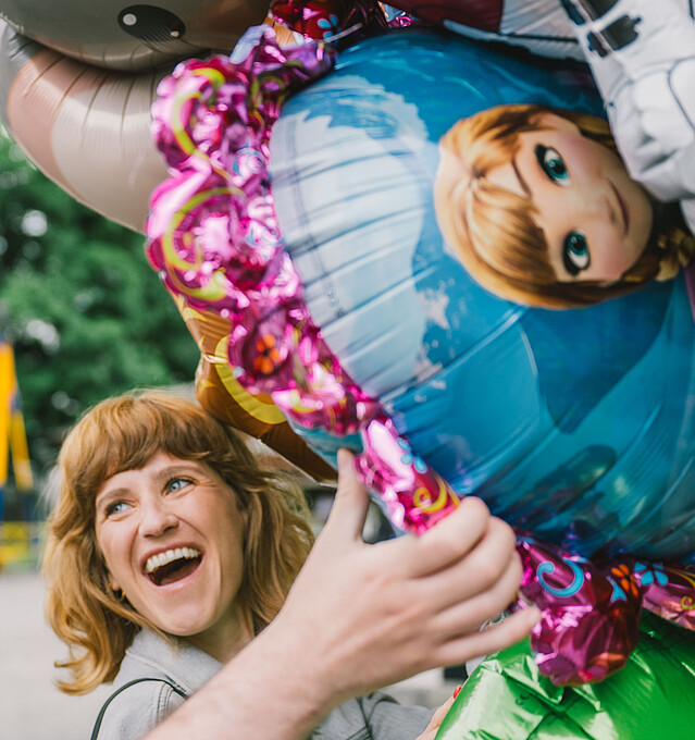 Eine Frau und ein Mann stehen lachend unter einer Traube Luftballons - Förderungen, Beratungen, Netzwerk für Unternehmen in Wien
