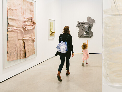 Eine Frau und ein kleines Mädchen in einer Kunstgalerie, das Mädchen deutet auf ein Kunstwerk